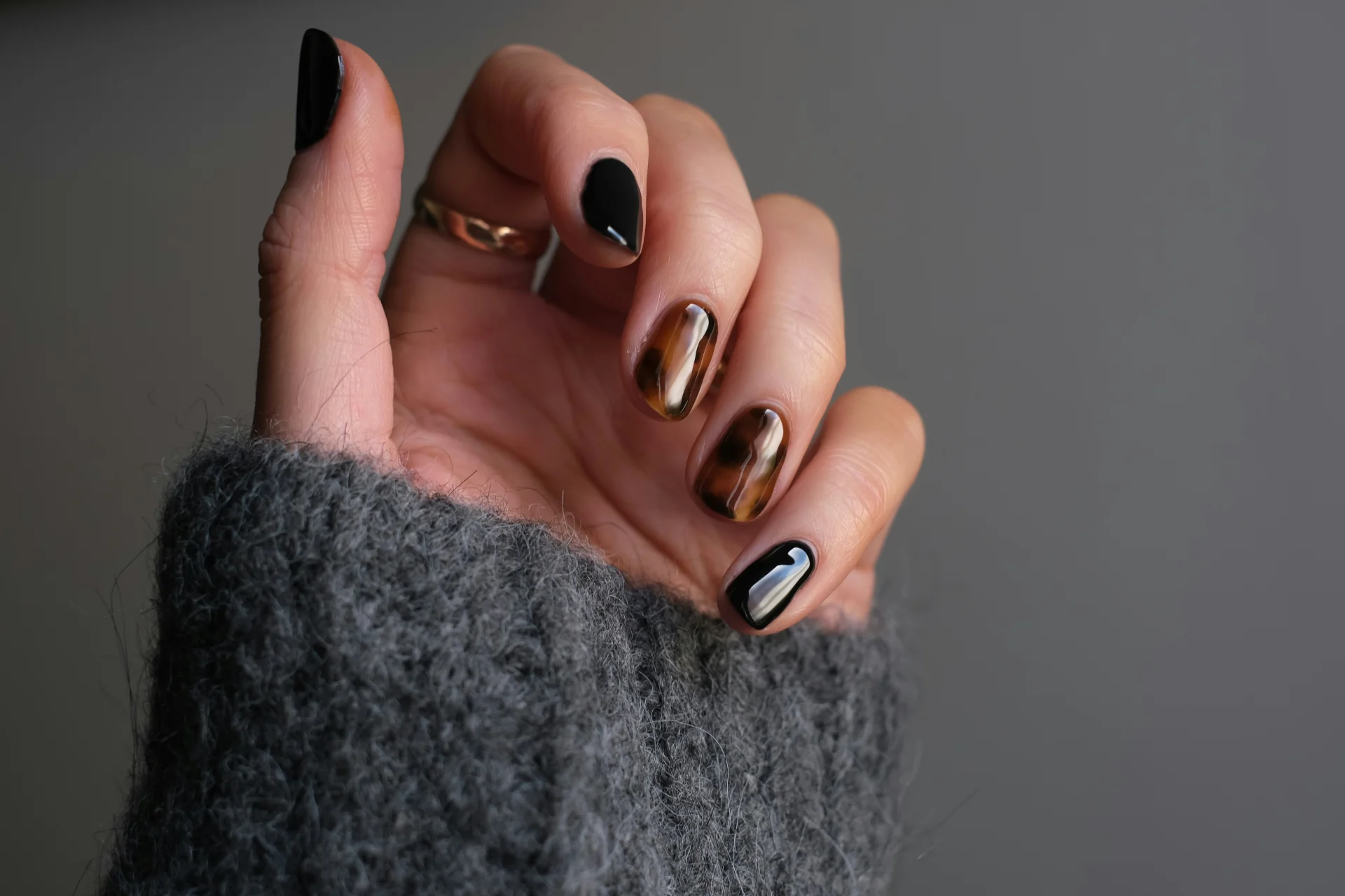 Zbliżenie na dłoń osoby noszącej srebrny pierścionek z czarnym manicure.