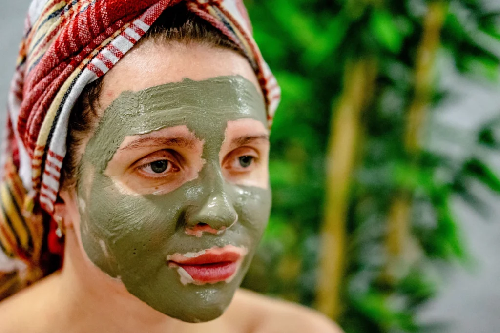 Kobieta relaksuje się podczas zabiegu z odmładzającą maseczką błotną w spa, dbając o skórę.